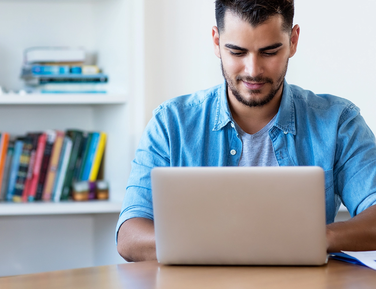 Man in blue shirt types on laptop