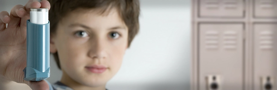 Young boy holds up an inhaler
