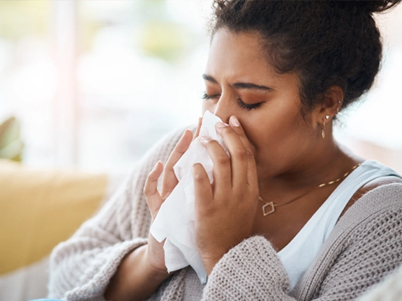 Woman blows her nose into a tissue.